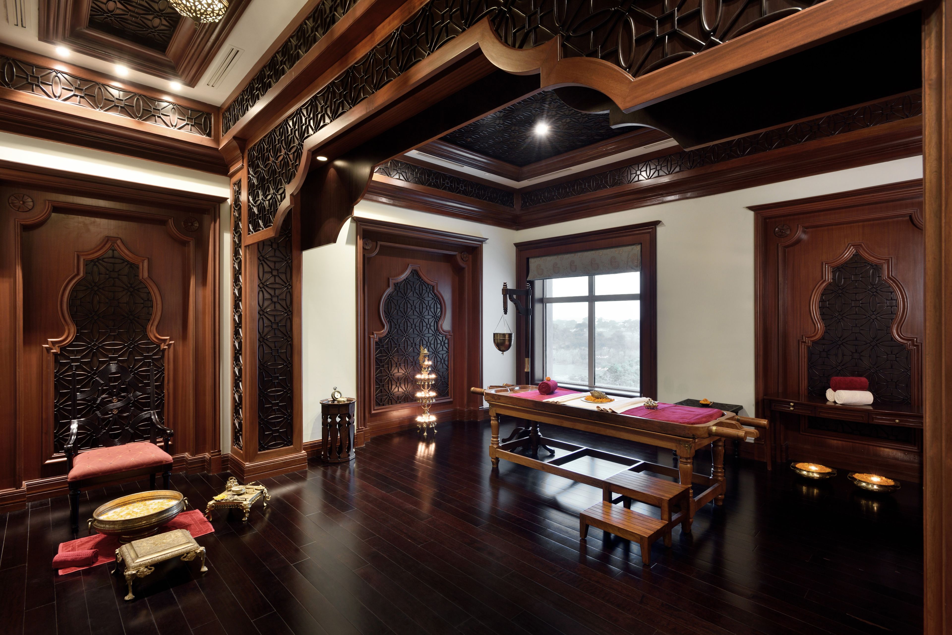 A traditional room with a wooden pool table, ornate wooden furniture, and a large window providing a view.