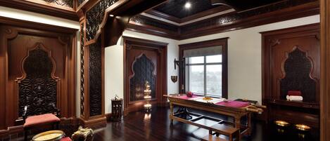 A traditional room with a wooden pool table, ornate wooden furniture, and a large window providing a view.