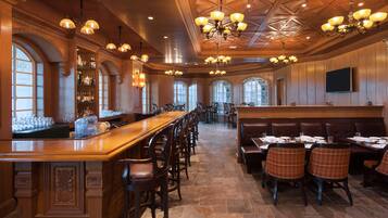 A spacious restaurant with high ceilings, wooden paneling, and multiple seating areas including a bar and booths.