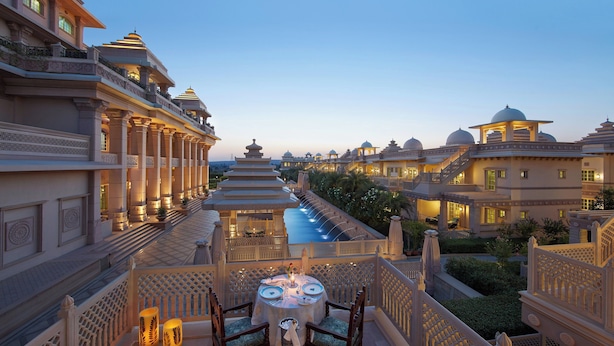 A luxurious hotel with a pool, ornate architecture, and a dining area with a table and chairs. - ITC Grand Bharat, a Luxury Collection Retreat, Gurgaon (Taoru)