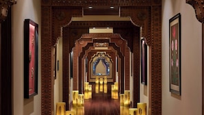 A corridor with ornate wooden arches, framed artwork, and illuminated decorative pillars. - ITC Grand Bharat, a Luxury Collection Retreat, Gurgaon (Taoru)
