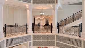 A grand, multi-level atrium with ornate railings, a chandelier, and a central seating area with sofas and a coffee table. - ITC Grand Bharat, a Luxury Collection Retreat, Gurgaon (Taoru)