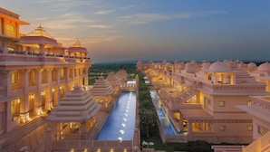 A large hotel with multiple buildings connected by a central pool, featuring traditional architecture and well-lit balconies. - ITC Grand Bharat, a Luxury Collection Retreat, Gurgaon (Taoru)
