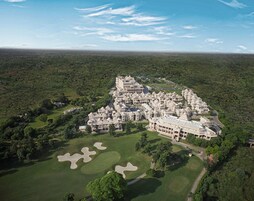 An aerial view of a large, sprawling resort with multiple buildings, expansive green lawns, and well-maintained pathways.