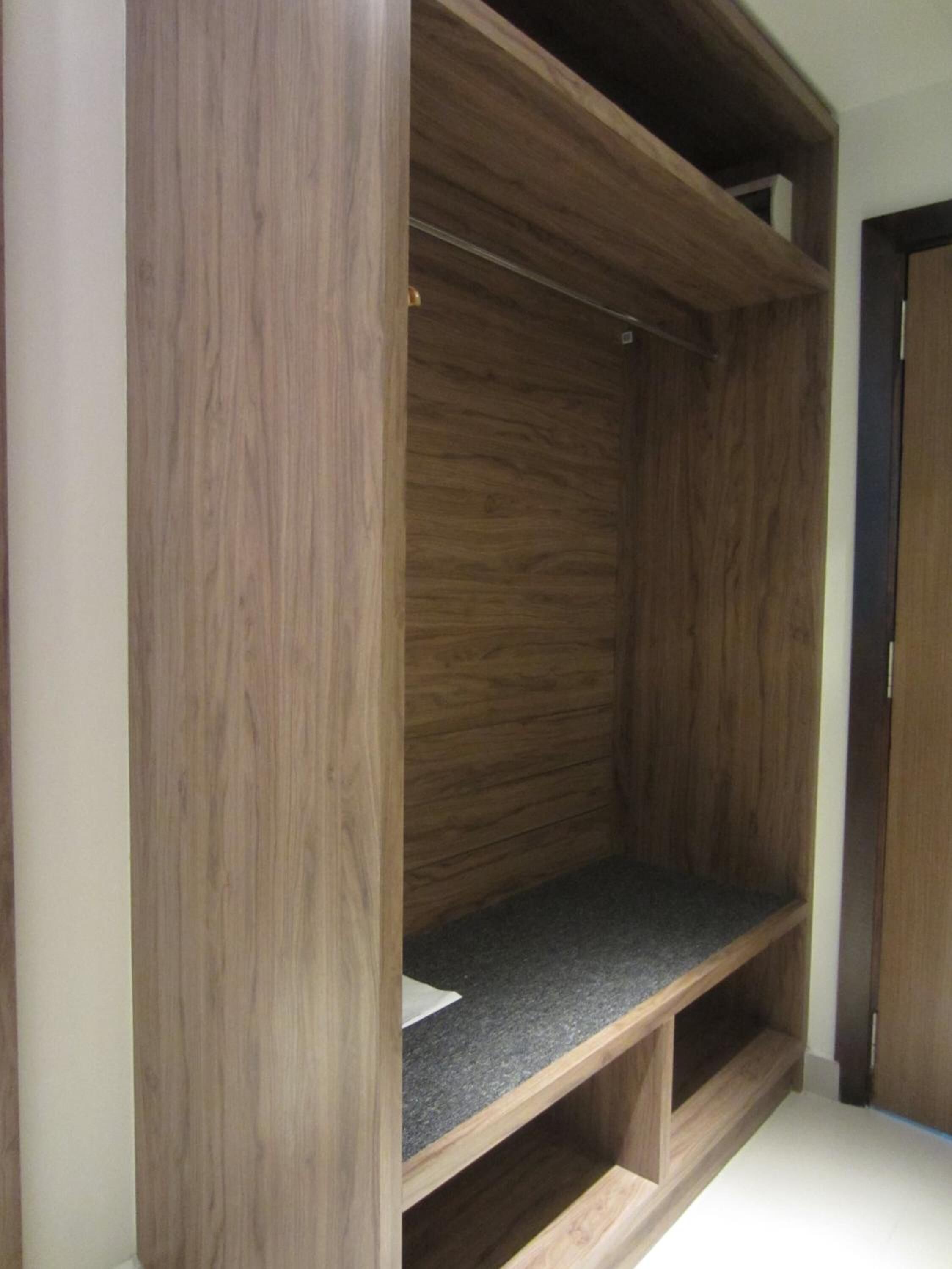 A wooden wardrobe with a shelf and a hanging space.
