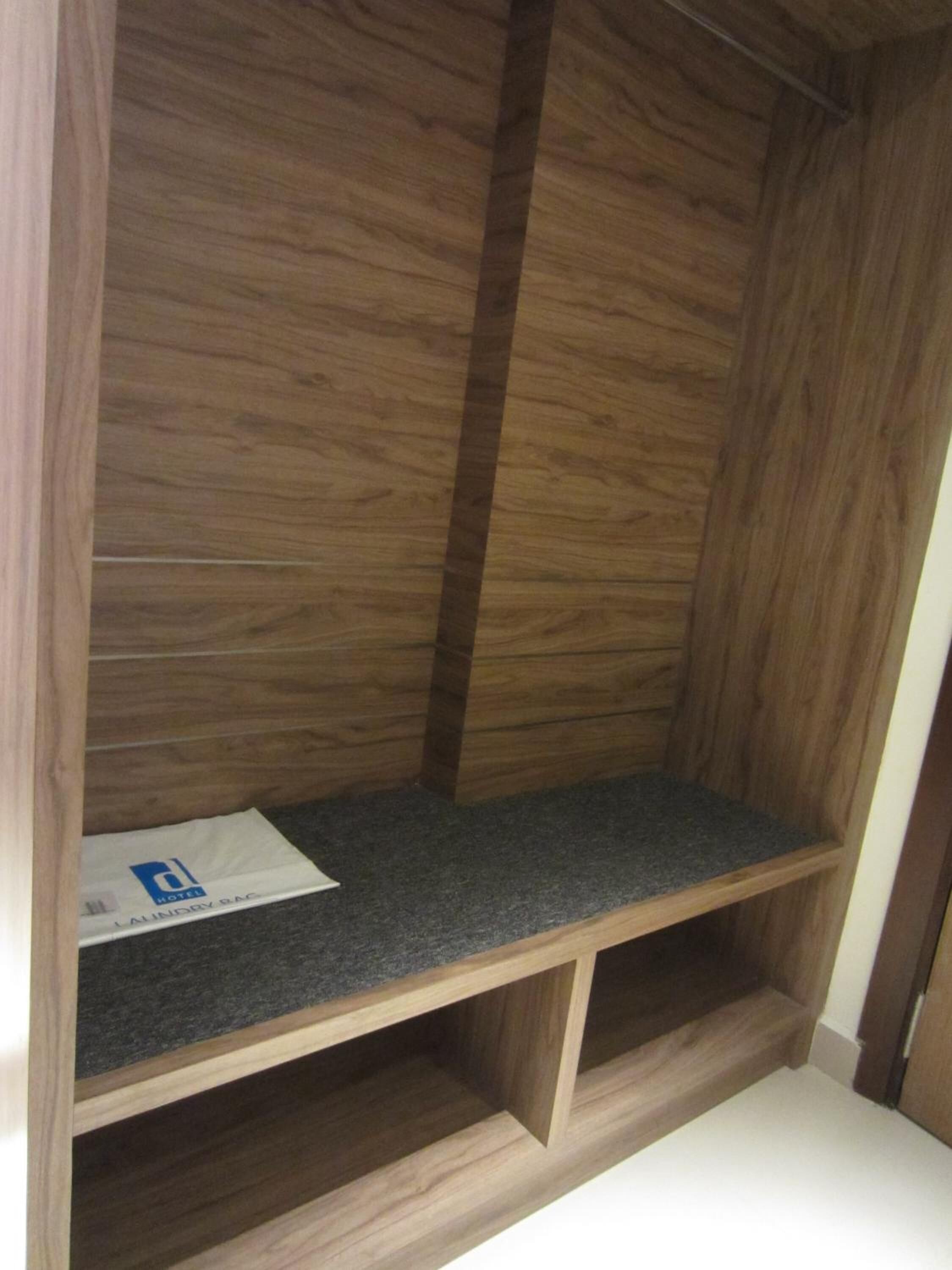 Une armoire en bois avec une étagère grise et un objet blanc posé dessus.