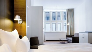 A modern hotel room with a large bed, a desk, a chair, and a window with curtains. - Motel One Prague-Florentinum (Prague)
