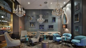 A modern lounge area with seating, chandeliers, and framed artwork on the walls. - Motel One Prague-Florentinum (Prague)