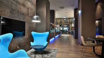 A modern lobby with a bar area, seating, and a television.
