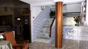 Un vestíbulo con una escalera, un mostrador de recepción y una zona de estar.