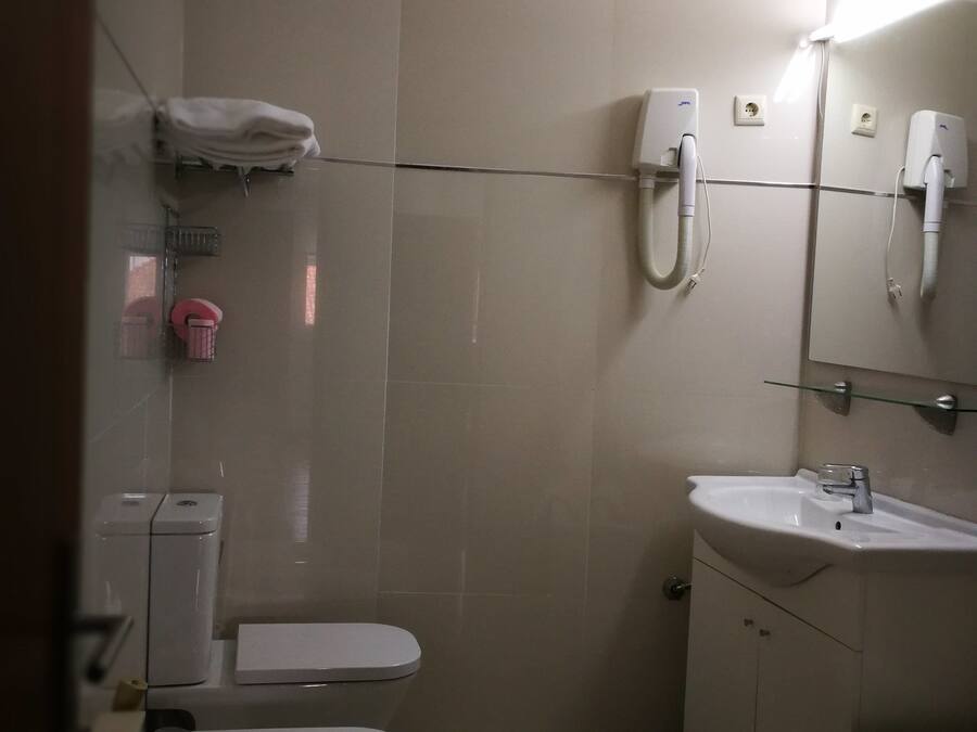 A small, well-lit bathroom with a toilet, bidet, sink, and a mirror above the sink.