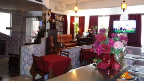 Una sala de estar con televisor, un sofá, una mesa de comedor con sillas y una zona de cocina con estufa.