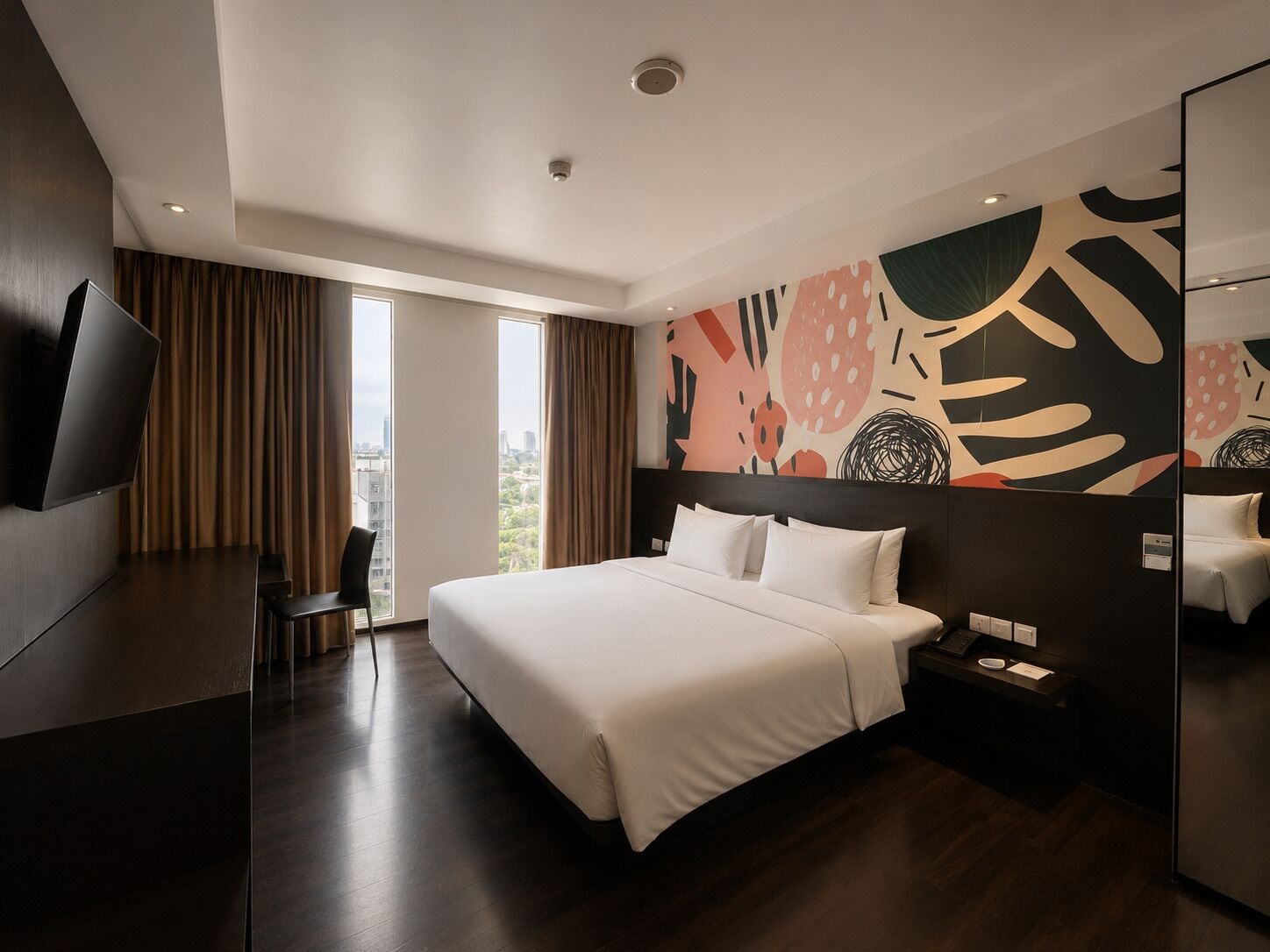 Een moderne hotelkamer met een groot bed, een flatscreen-tv, een bureau en uitzicht over de stad.
