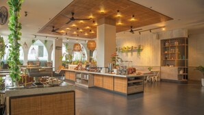 Een modern restaurant met een centraal eiland, zitgedeeltes en verschillende planten.