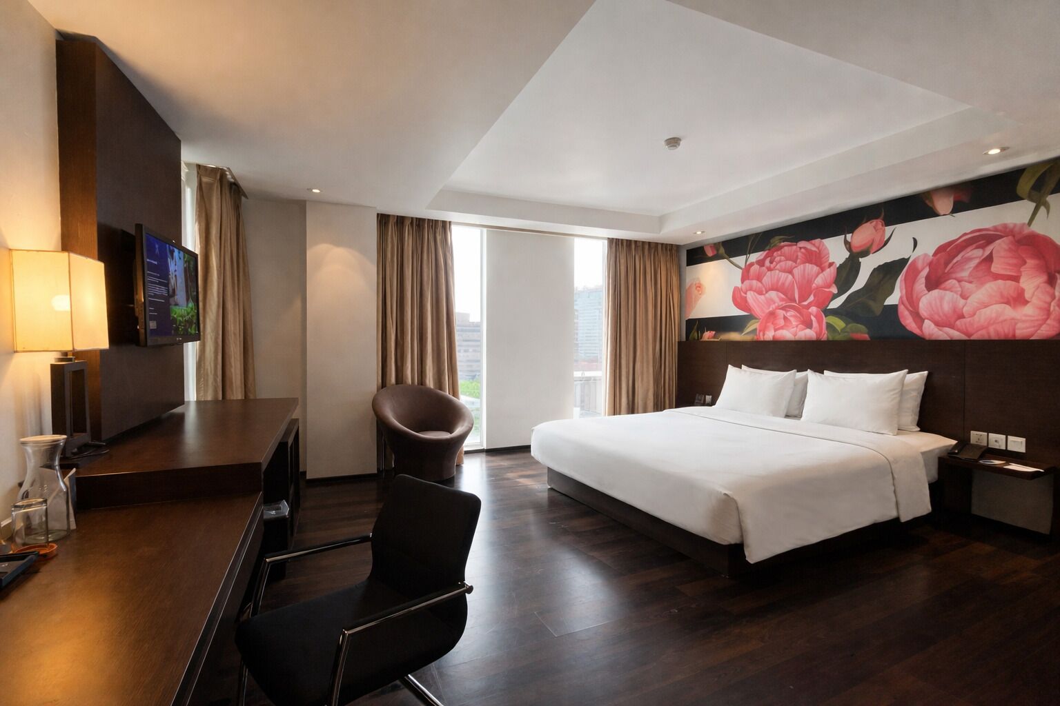Una camera d'albergo con un letto, una scrivania, una sedia e un'ampia finestra.