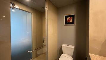 Een moderne badkamer met een douchecabine van glas, een toilet en een ingelijst schilderij aan de muur.