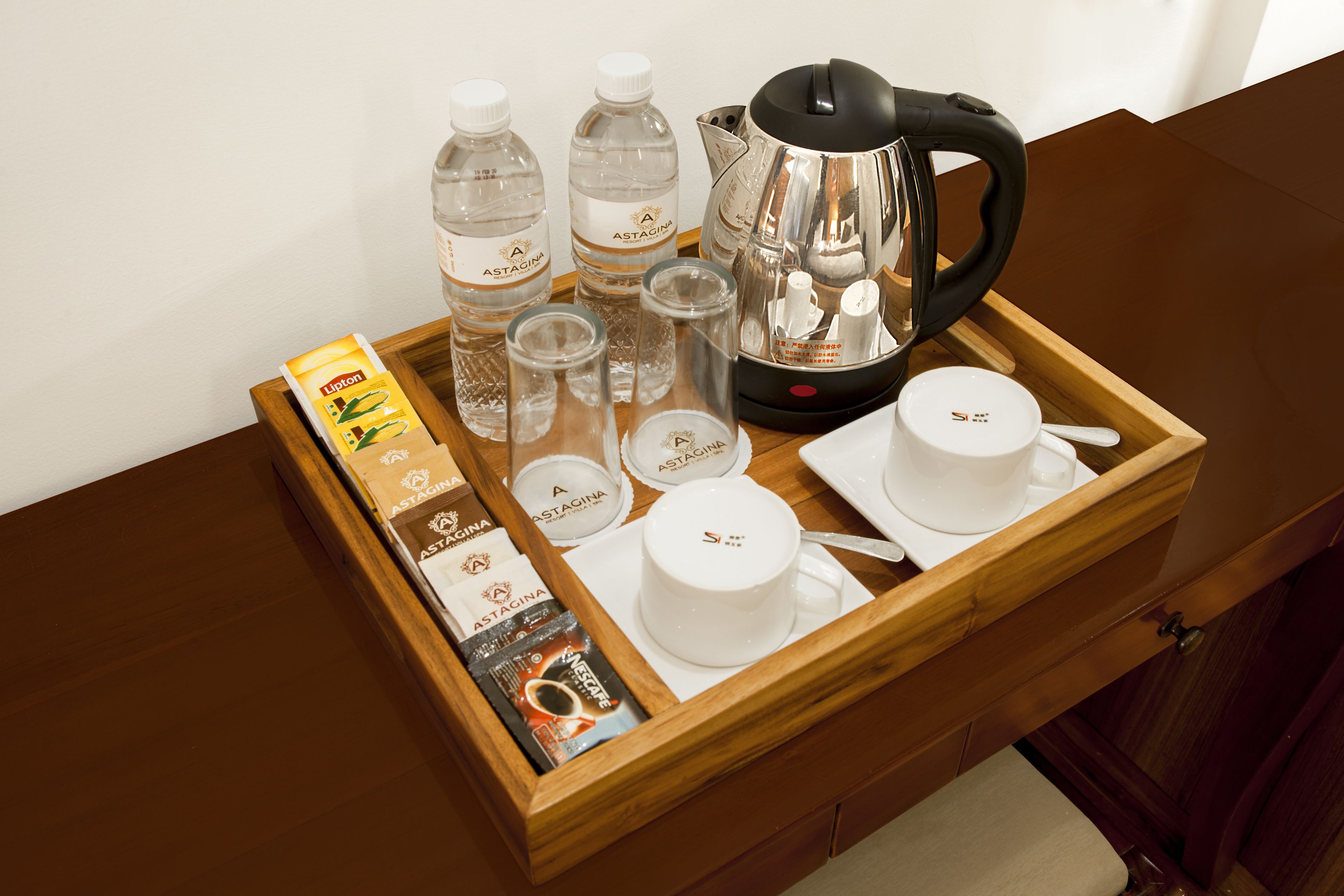A wooden tray with a coffee maker, cups, glasses, and a Lipton tea box.