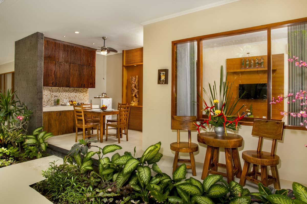 A modern kitchen with wooden cabinets, a dining area with a table and chairs, and a large window with a view of the outdoors.