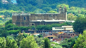 A historic building with a bell tower, surrounded by lush greenery and residential buildings.