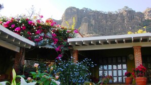 A building with a brick facade, a covered porch area, and a view of a mountainous landscape in the background.