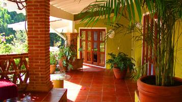 Un patio cubierto con baldosas de terracota, plantas en macetas y un banco de madera.