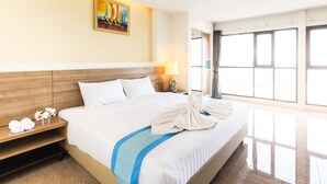 A hotel room with a large bed, a nightstand with a lamp, a painting on the wall, and a window with curtains.