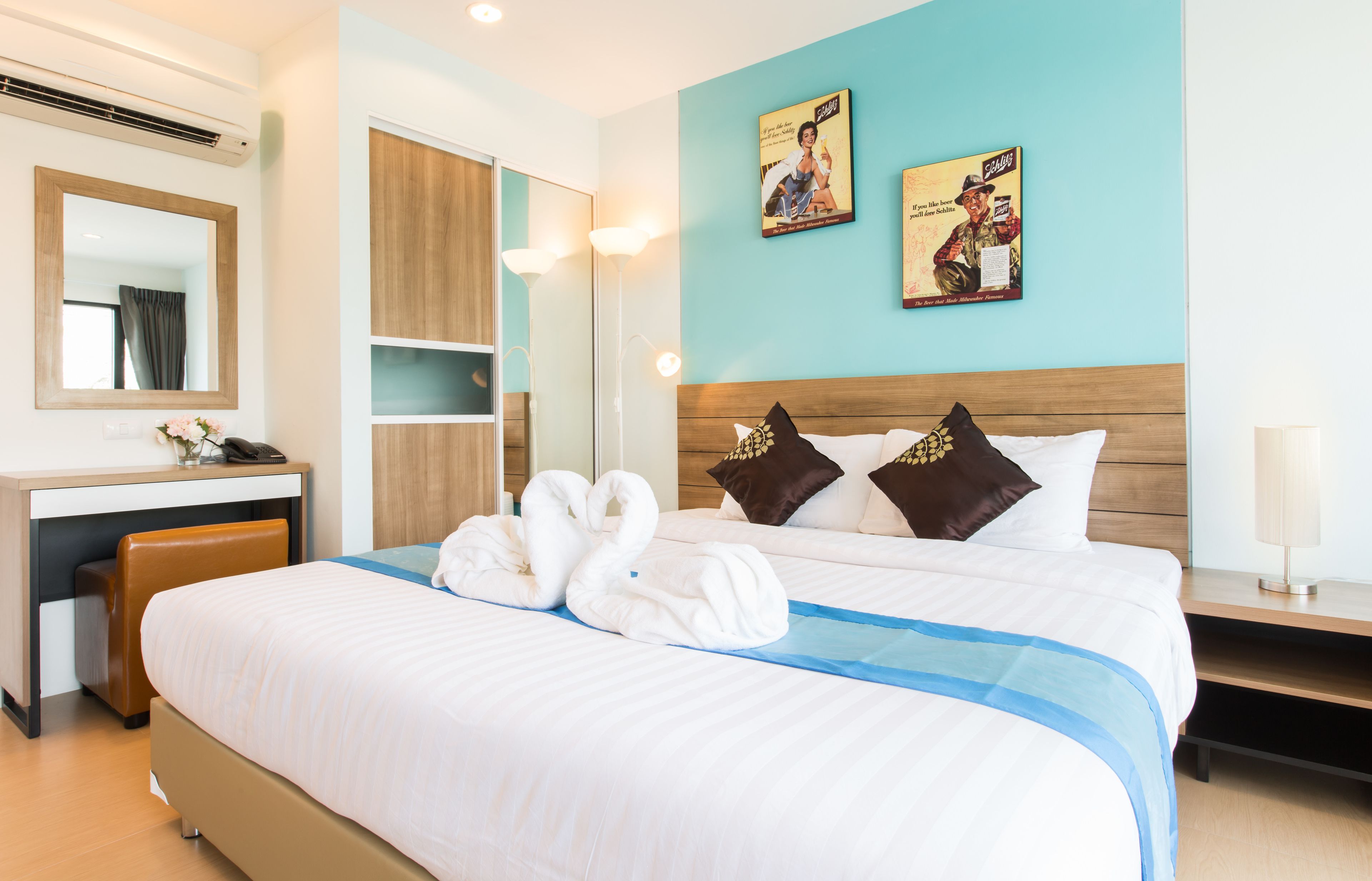 Hotelkamer met een groot bed, een bureau, een stoel, een spiegel en twee decoratieve wandpanelen.