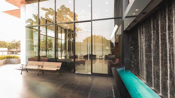 A modern building with large glass windows, a bench, and a water feature.