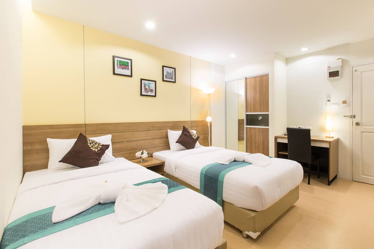 Habitación de hotel con dos camas, un escritorio y un espejo.