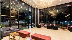 A modern lobby with large windows, plush seating, and a chandelier.