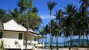 A beachfront property with a single-story house, surrounded by palm trees and a clear view of the ocean. - Jinta Beach Bungalow (Koh Samui)