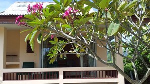 A building with a balcony, a tree with pink flowers, and a clear sky. - Jinta Beach Bungalow (Koh Samui)