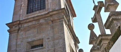 Una torre de piedra con tejado de baldosas y un ave posada en la parte superior.