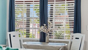 A room with a window, a table, two chairs, and a vase with flowers.