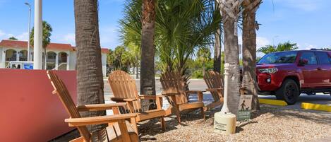 Outdoor seating with wooden chairs and a red vehicle parked nearby.