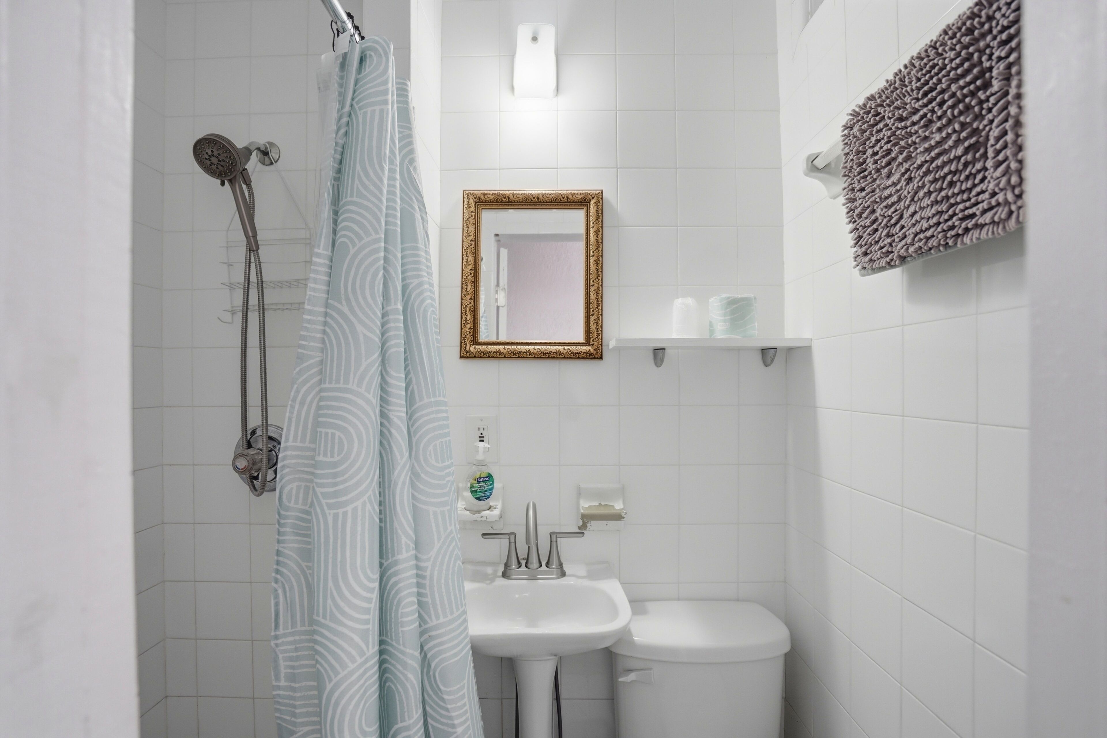 A bathroom with a shower, sink, toilet, and a towel rack.