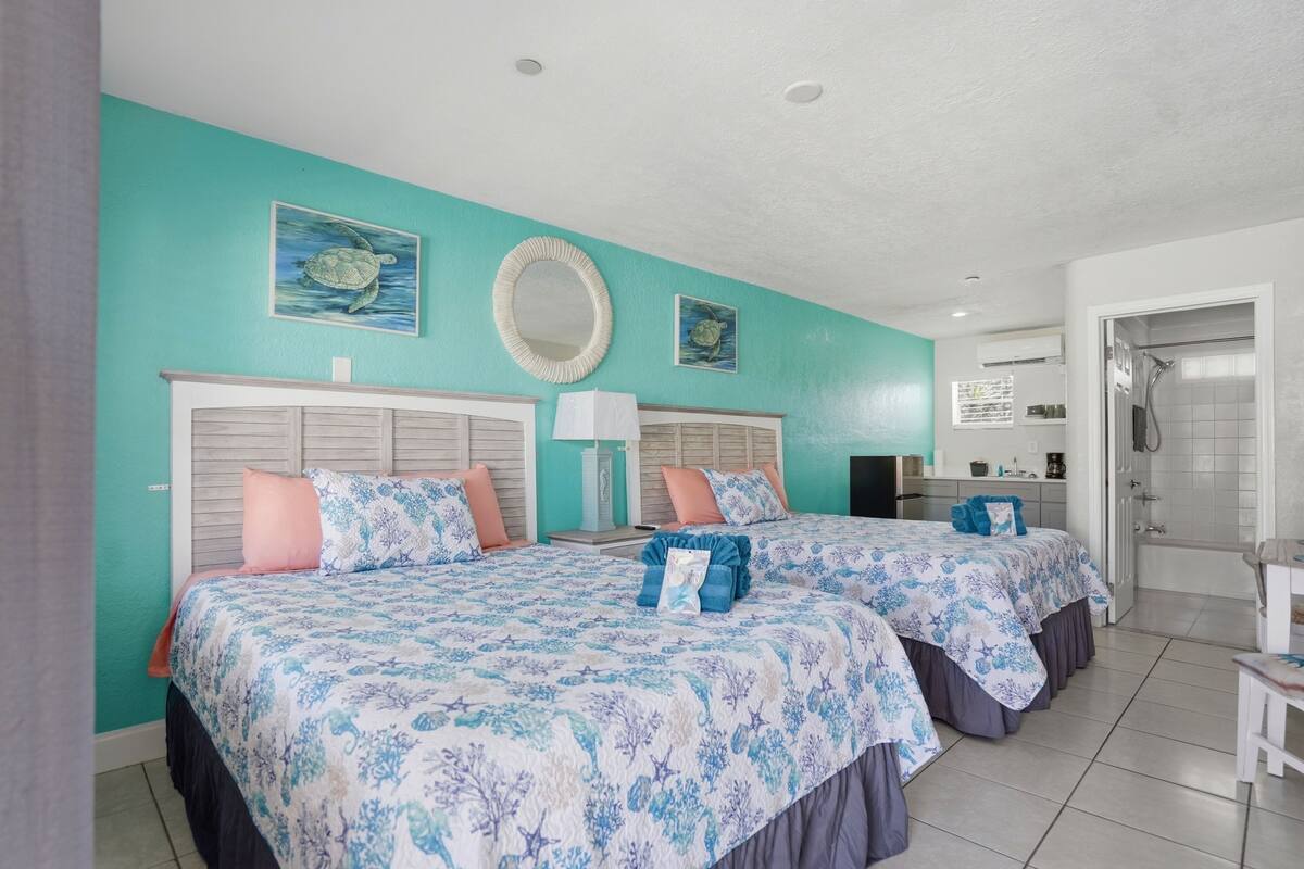 A room with two beds, a bathroom, and a shower.