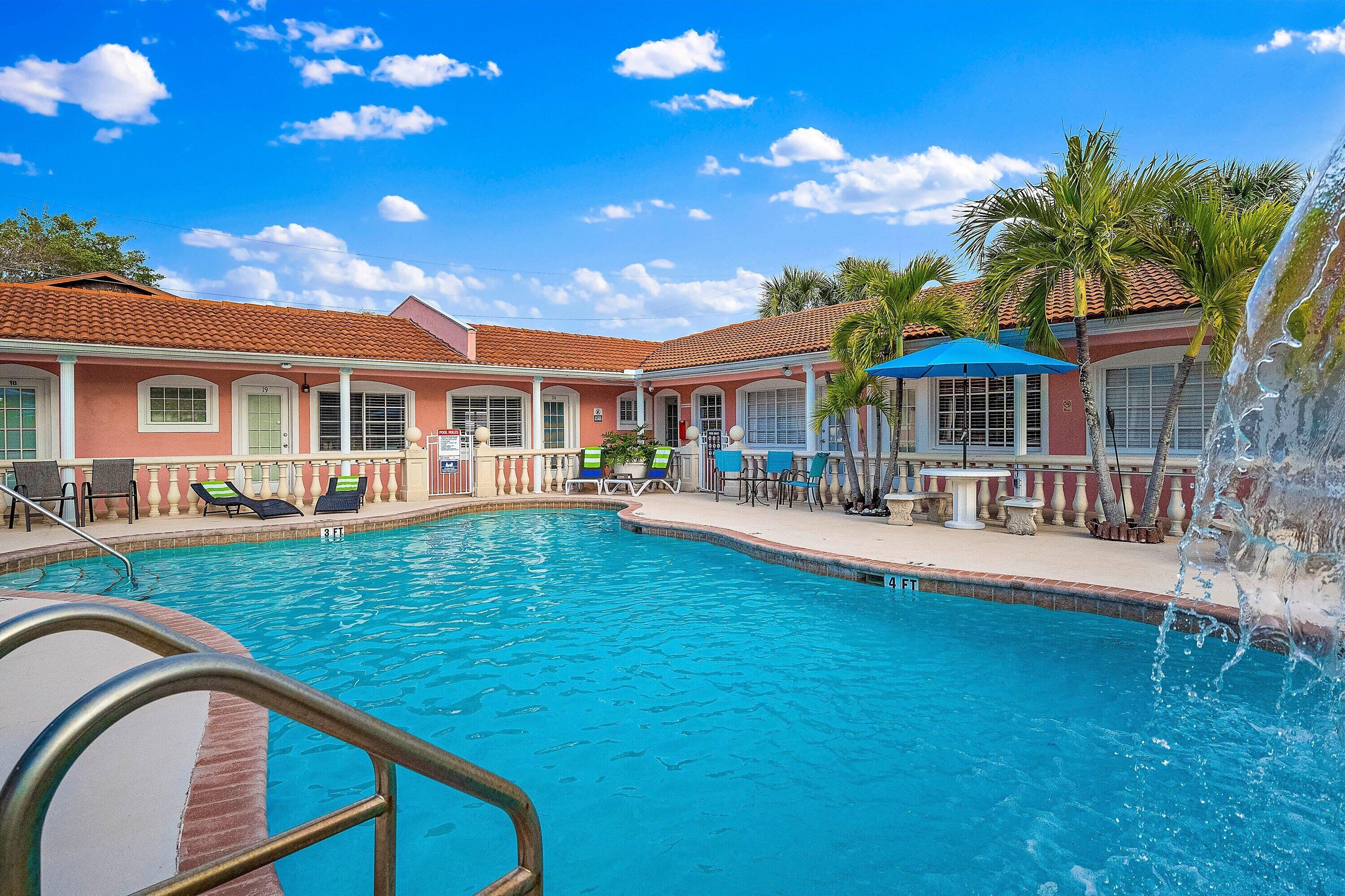 A swimming pool with lounge chairs and a water fountain.