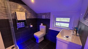 A modern bathroom with a toilet, sink, and shower area. - Charlotte Guest House (London)