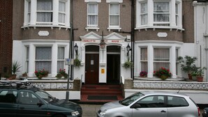 A two-story townhouse with bay windows, a front entrance with steps, and potted plants. - Charlotte Guest House (London)