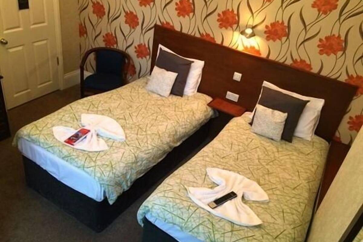 A hotel room with two beds, each with a neatly folded towel and a remote control.