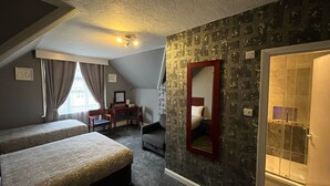 A hotel room with two beds, a desk, a chair, a mirror, and a shower area. - Charlotte Guest House (London)