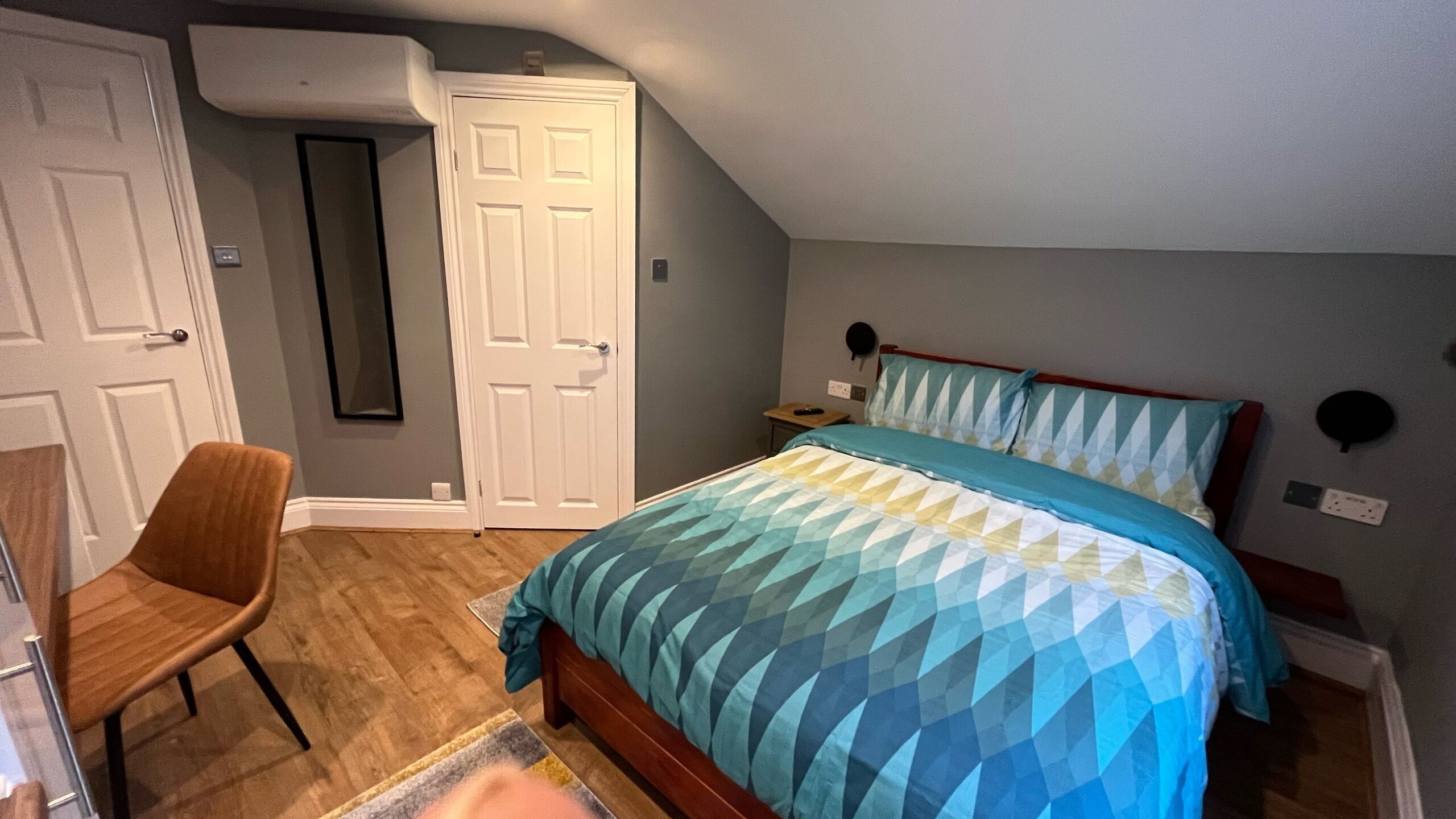 A bedroom with a bed, a chair, and a door.