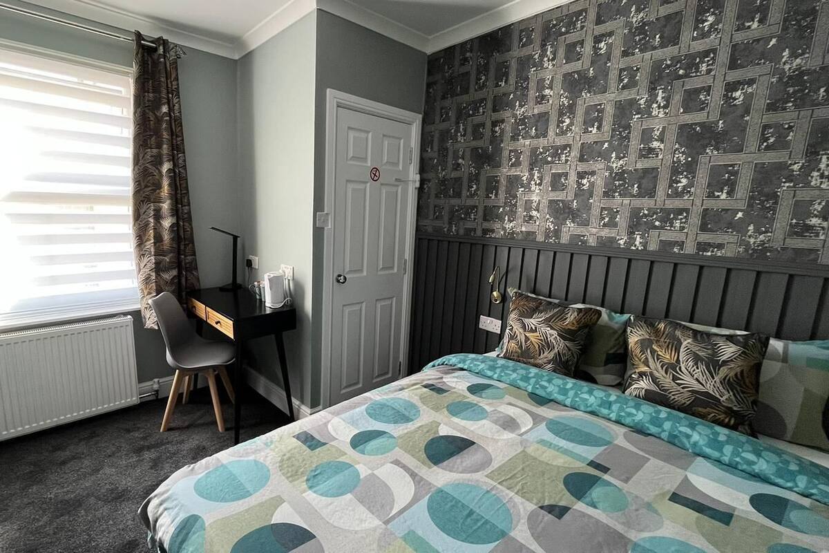 A bedroom with a bed, a desk, and a radiator.