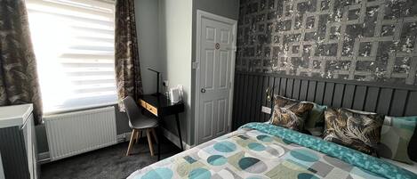 Une chambre à coucher avec un lit, un bureau et un radiateur.