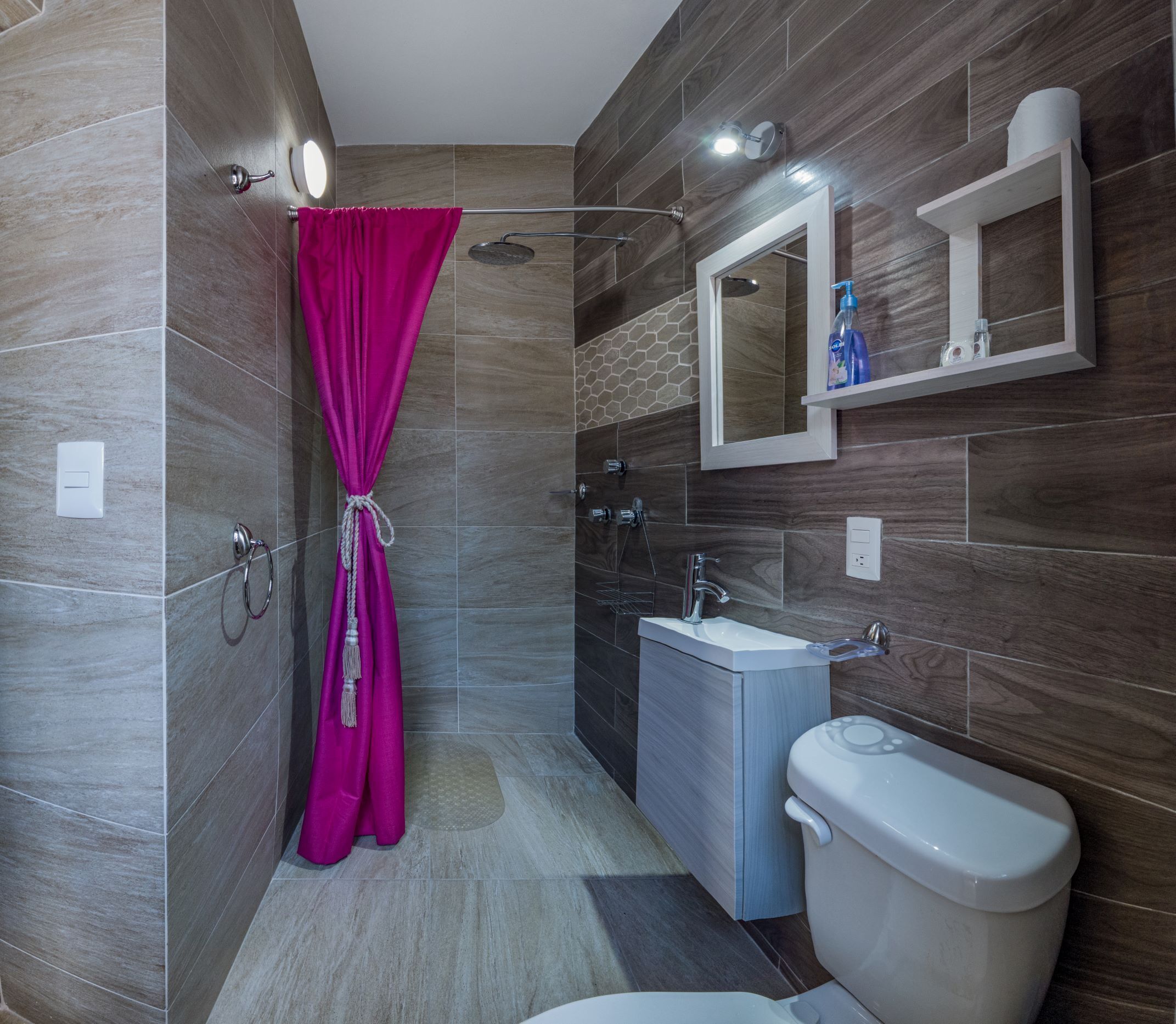 A modern bathroom with a shower, toilet, sink, and a mirror.