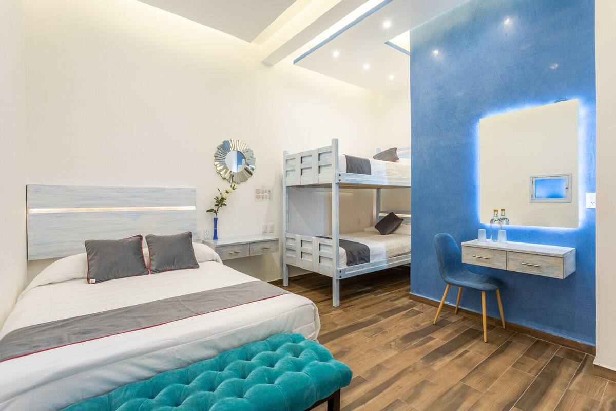 A modern bedroom with a bunk bed, a desk with a chair, and a large mirror.