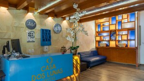 A hotel reception area with a blue counter, a clock, and a display of local crafts. - Hotel Dos Lunas - Hostel (Oaxaca)