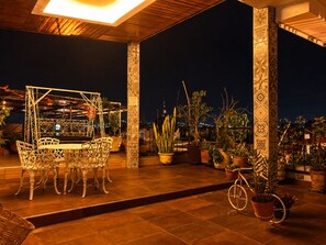 An outdoor patio with a dining set, potted plants, and a bicycle. - Hotel Dos Lunas - Hostel (Oaxaca)
