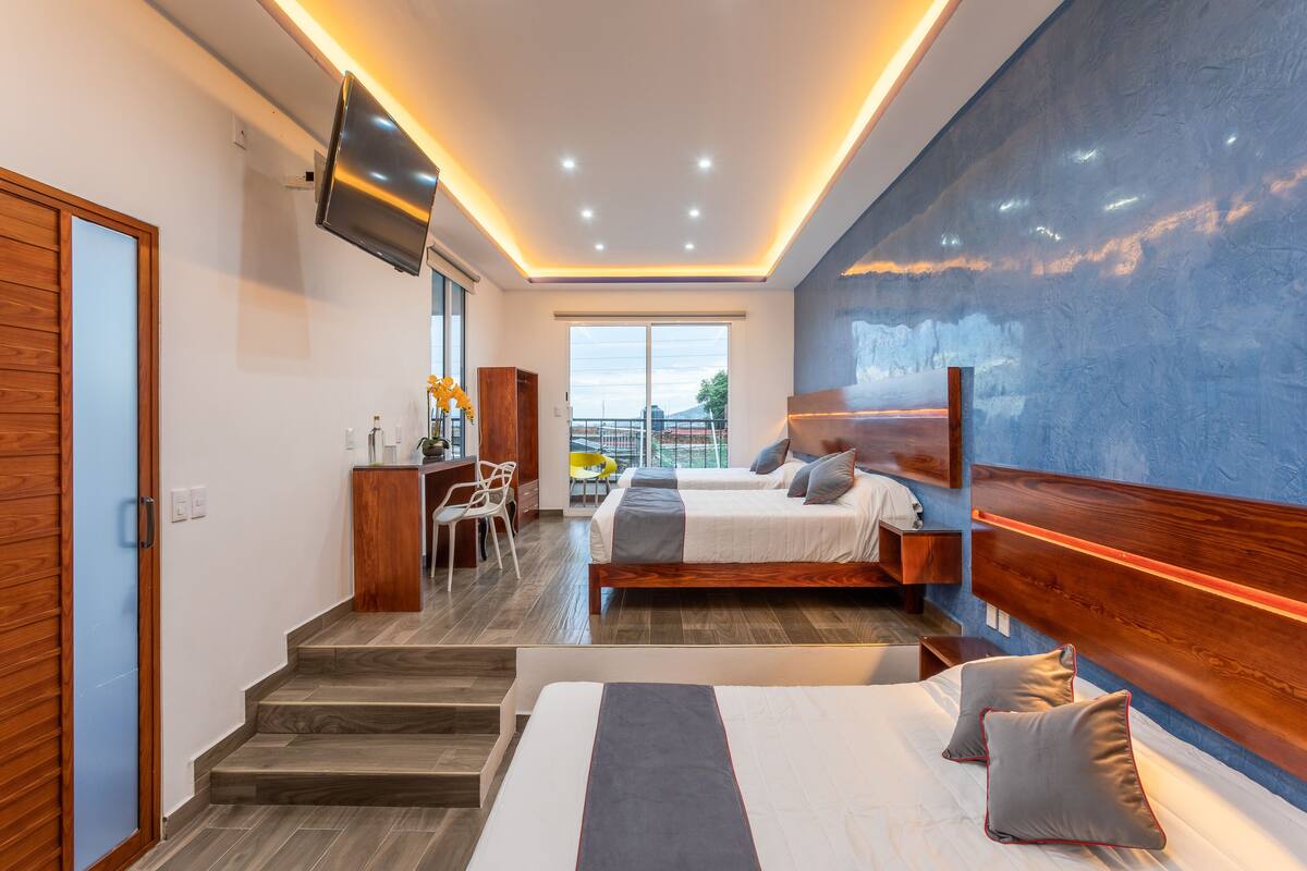 A modern hotel room with a large bed, a desk, and a balcony with a view.